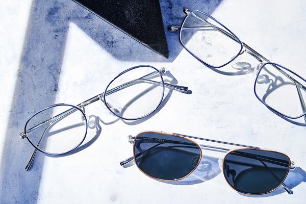 Eyeglasses on a blue and white surface featuring Warby Parker's Eshi Edition collection. Image courtesy of Warby Parker.