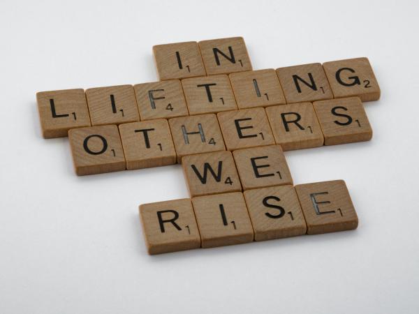 Scrabble letters spell out "In lifting others, we rise." Photo by Brett Jordan on Unsplash.